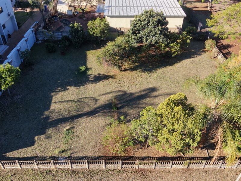 Aerial view of a residential vacant land plot featuring established trees and perimeter boundary walls.