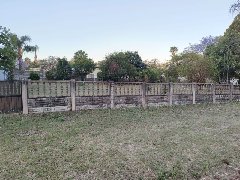 A view of the front boundary featuring a precast concrete wall with decorative balustrades and a metal entrance gate on a residential plot.