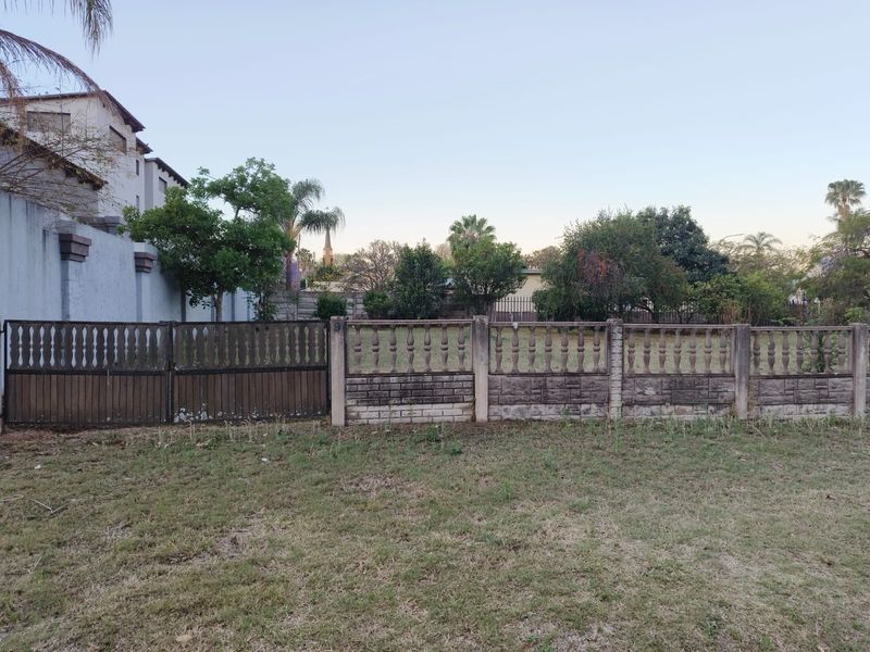 A view of the front boundary featuring a precast concrete wall with decorative balustrade detailing and a metal driveway gate.