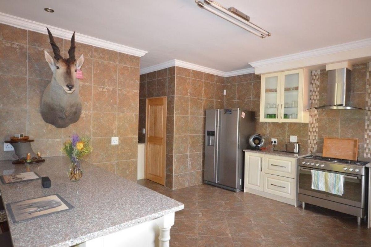 Spacious kitchen featuring granite countertops, tiled wall finishes, and a stainless steel gas stove with extractor fan.