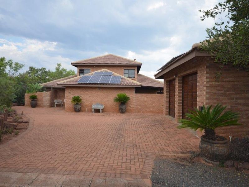 Front elevation of a facebrick house featuring a paved driveway, double garage, and roof-mounted solar panels.