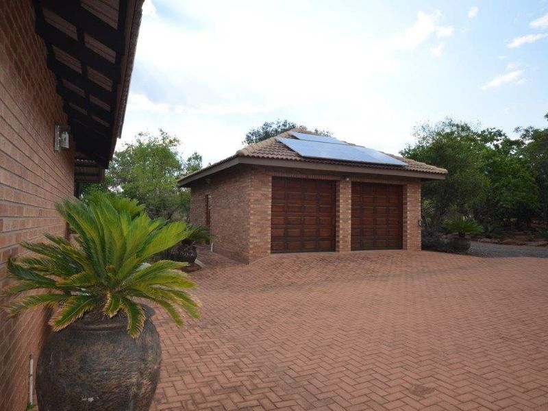 A well-maintained facebrick double garage featuring a tiled roof with integrated solar panels and extensive brick-paved driveway space.