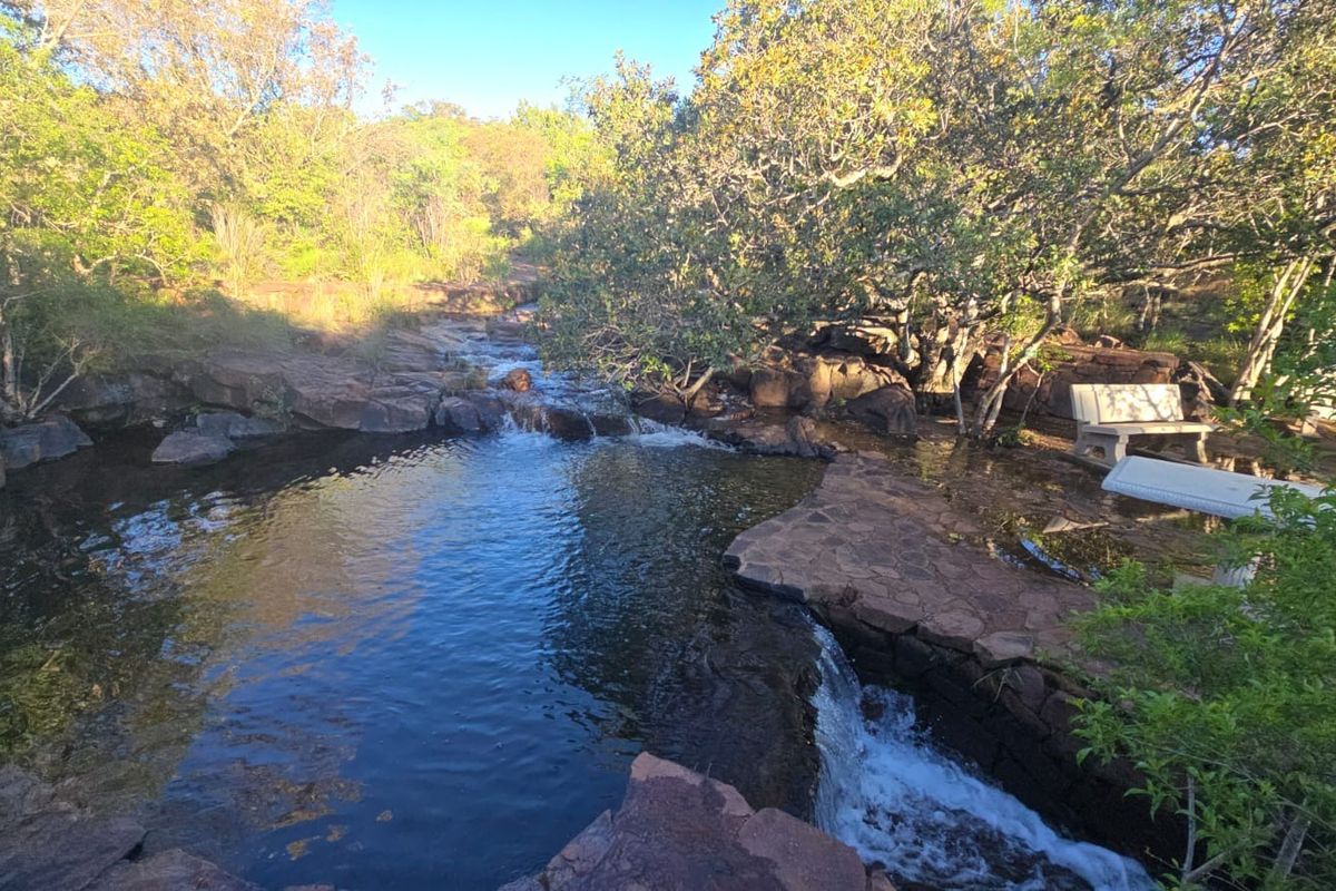A scenic natural rock pool and waterfall feature set within a lush, landscaped garden environment.