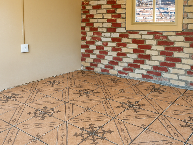An empty bedroom featuring a distinctive exposed brick feature wall, patterned ceramic floor tiles, and a sliding window.