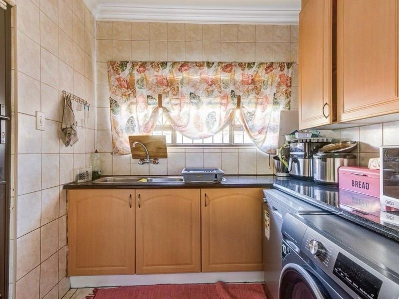 Functional scullery area featuring built-in cabinetry, laminate countertops, a stainless steel sink, and dedicated space for laundry appliances.