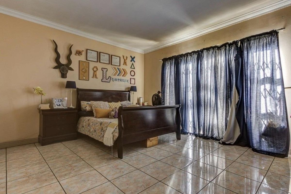 Spacious bedroom featuring tiled flooring, crown molding, and a sliding glass door with an integrated security gate providing access to the exterior.