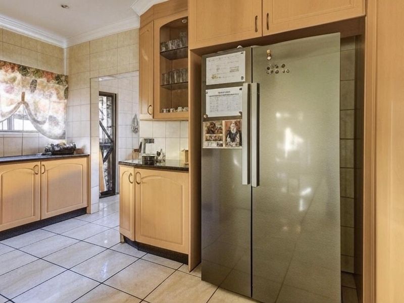 A functional kitchen featuring light wood cabinetry, granite countertops, tiled flooring, and a tiled backsplash, offering a classic and practical layout.