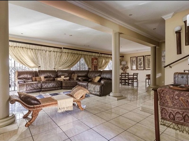 Spacious open-plan living and dining area featuring large structural columns, tiled flooring, and recessed lighting, offering a versatile layout for family living.