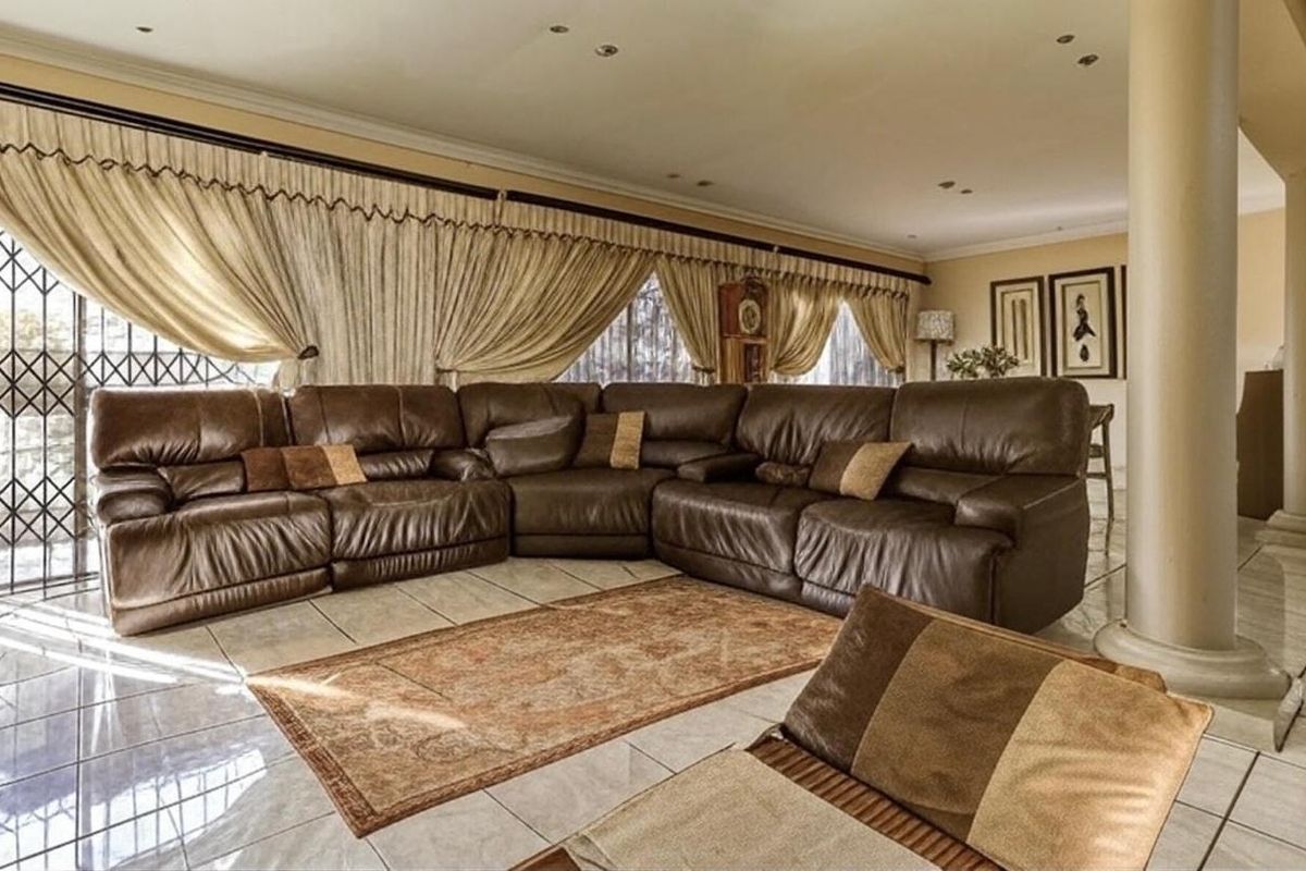 Spacious living area featuring large format floor tiles, a structural column, and access to the exterior through a security gate.