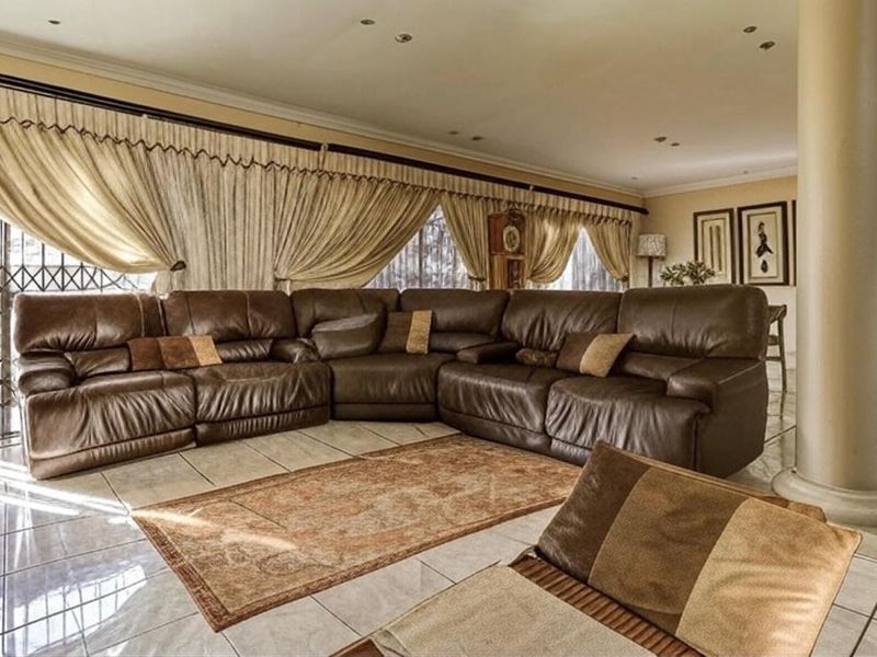 Spacious living area featuring large format floor tiles, a structural column, and access to the exterior through a security gate.