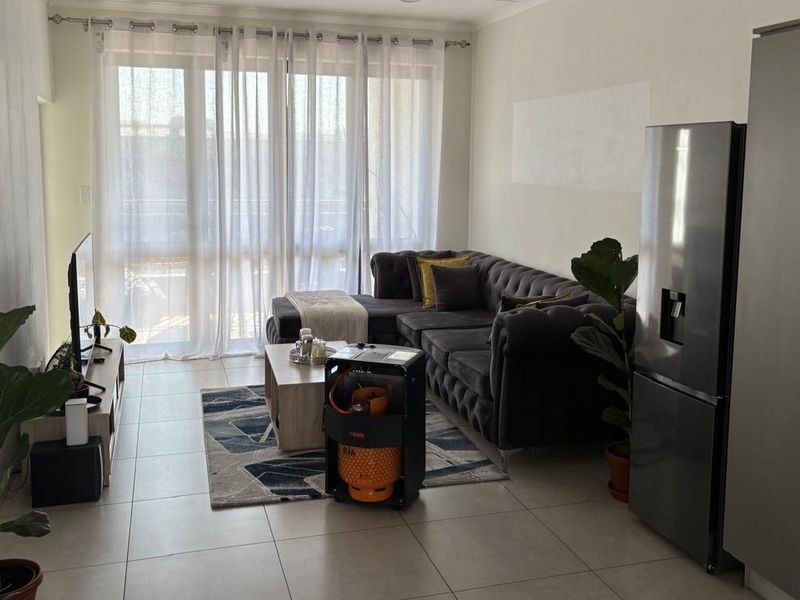 Open plan living area featuring tiled floors and a sliding glass door leading to an outdoor space, adjacent to a modern kitchen.