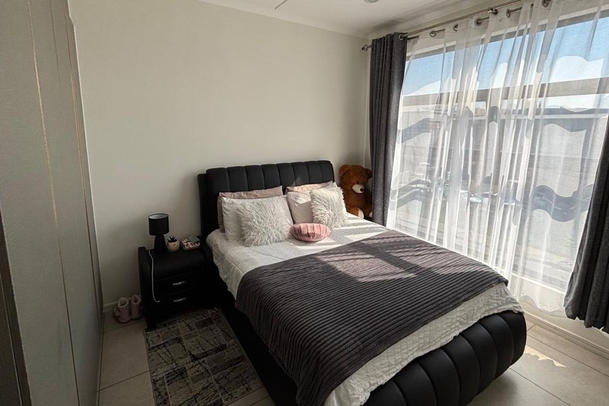 A well-lit bedroom featuring tiled flooring, built-in cupboards, and a large sliding glass door providing access to an outdoor area.