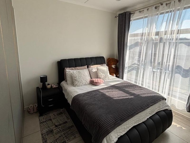 A well-lit bedroom featuring tiled flooring, built-in cupboards, and a large sliding glass door providing access to an outdoor area.