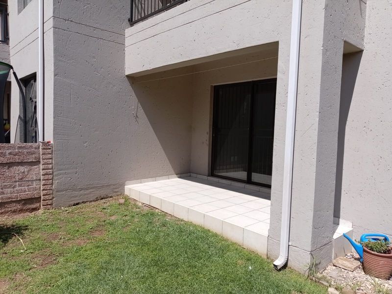 A covered ground-floor patio with tiled flooring and a sliding glass door, providing direct access to the garden area.