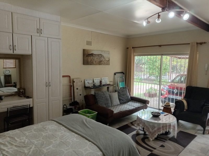 Spacious bedroom featuring built-in cupboards, tiled flooring, and a sliding glass door providing direct access to the exterior.