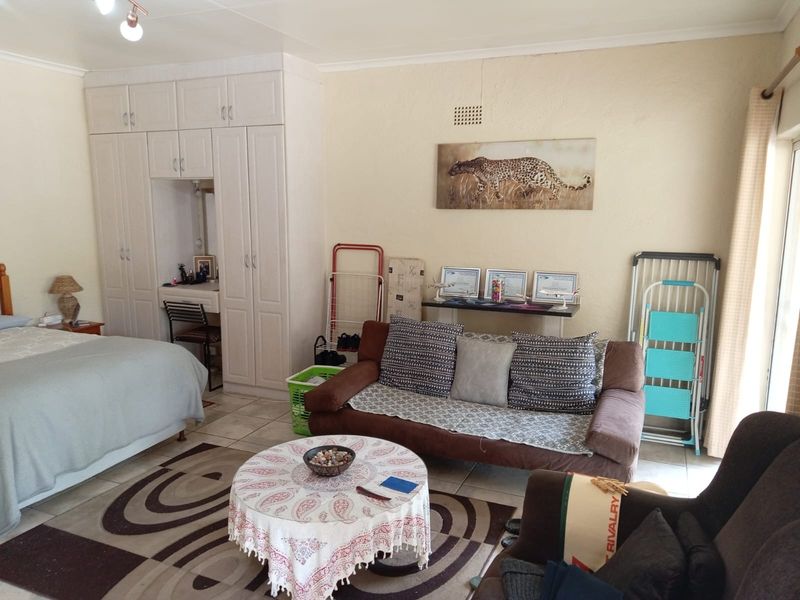 Spacious bedroom featuring built-in cupboards, tiled flooring, and direct access to outdoor space, offering a functional layout with potential for modern updates.