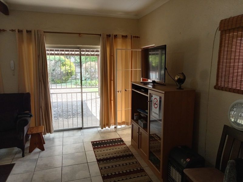Living room featuring tiled flooring and a sliding glass door with security gate, providing direct access to the outdoor area.