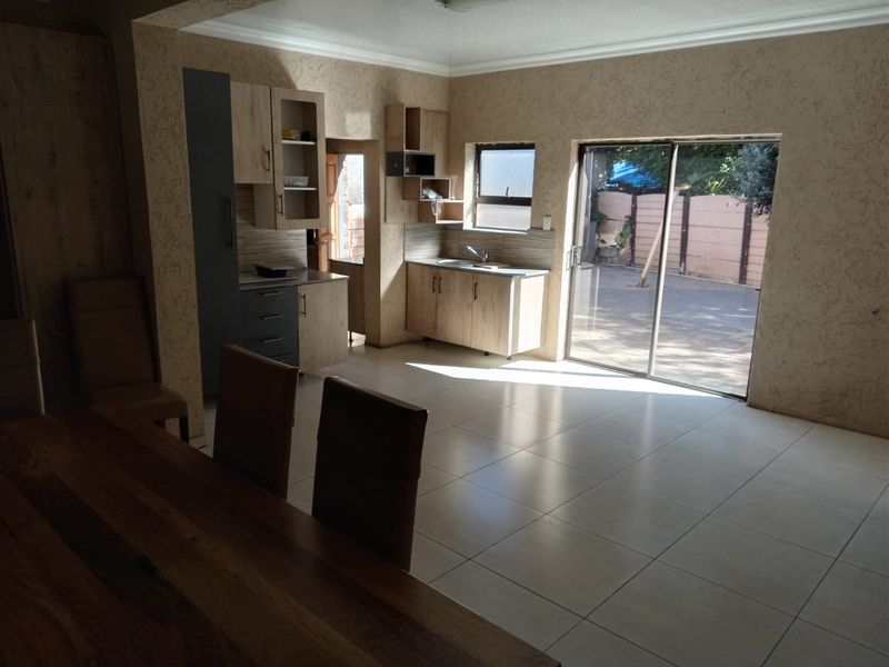 Open plan kitchen and living area featuring modern cabinetry, tiled flooring, and direct access to the rear patio through a sliding glass door.
