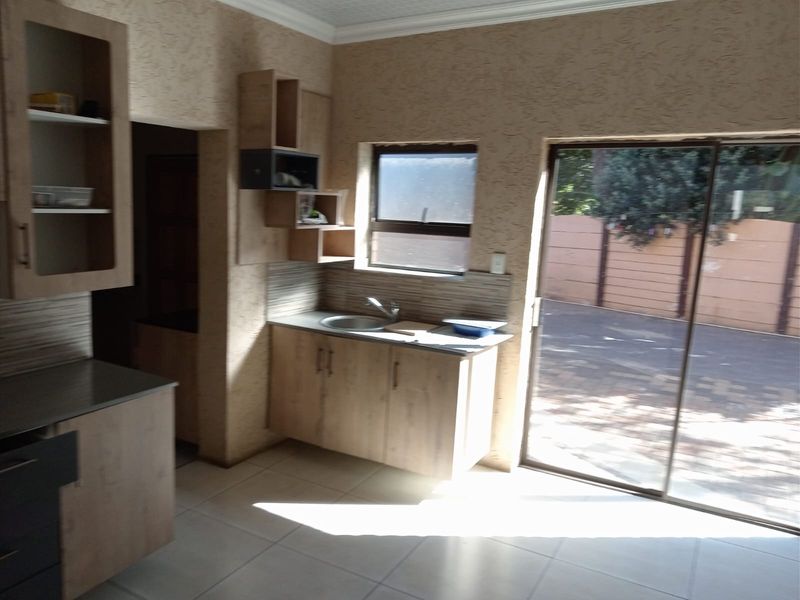 A functional kitchen area featuring built-in cabinetry, a stainless steel sink, and direct access to the exterior through a sliding glass door.