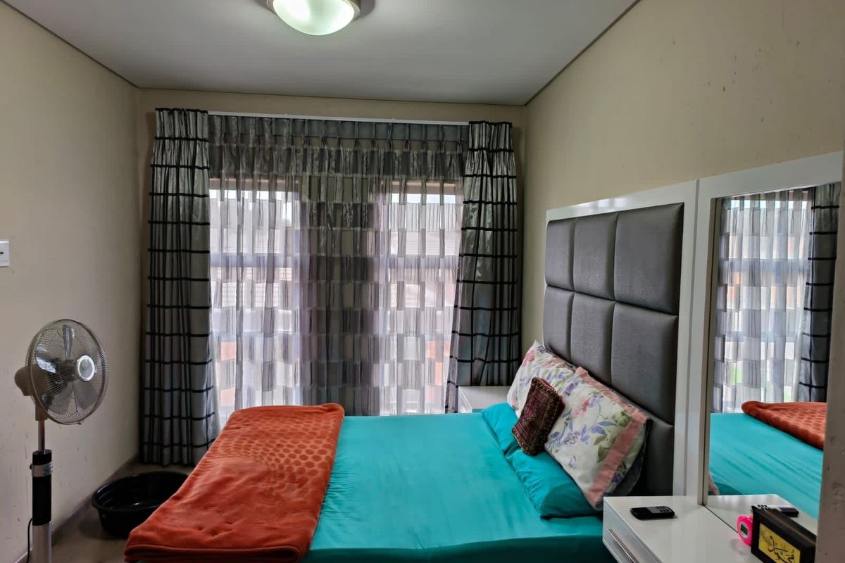 A bedroom featuring a large window with floor-to-ceiling curtains, providing natural light and a view of the exterior.