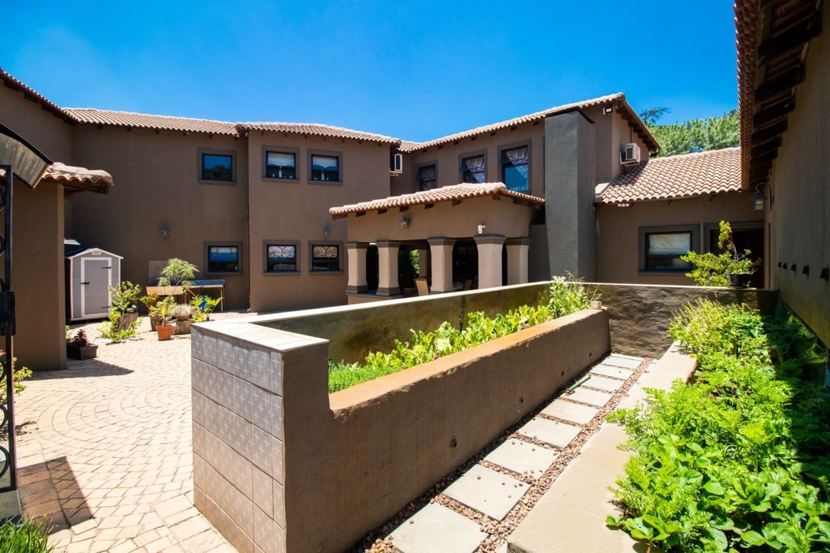 A spacious rear courtyard featuring paved flooring, a built-in raised planter box, and a covered patio area attached to the main house structure.