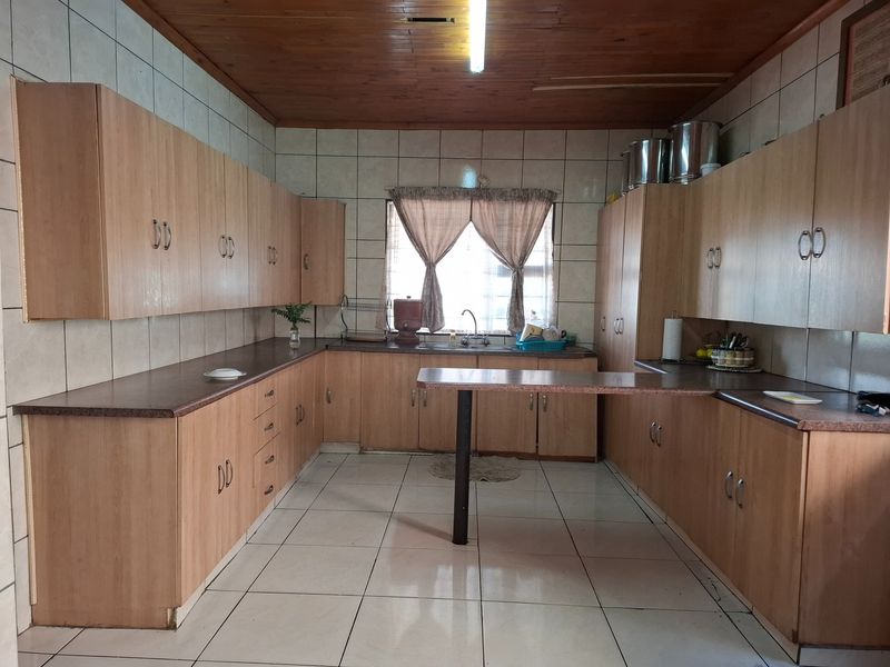 Spacious kitchen featuring extensive laminate cabinetry, tiled flooring, a timber ceiling, and a functional breakfast bar layout.