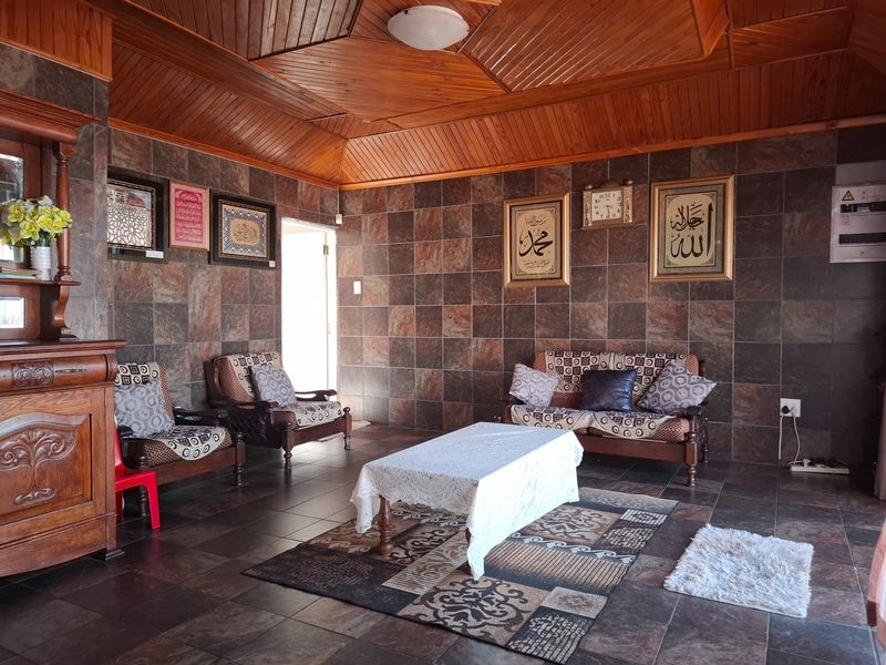 Spacious living area featuring distinctive timber-clad vaulted ceilings and full-height tiled wall finishes, creating a unique and textured interior aesthetic.