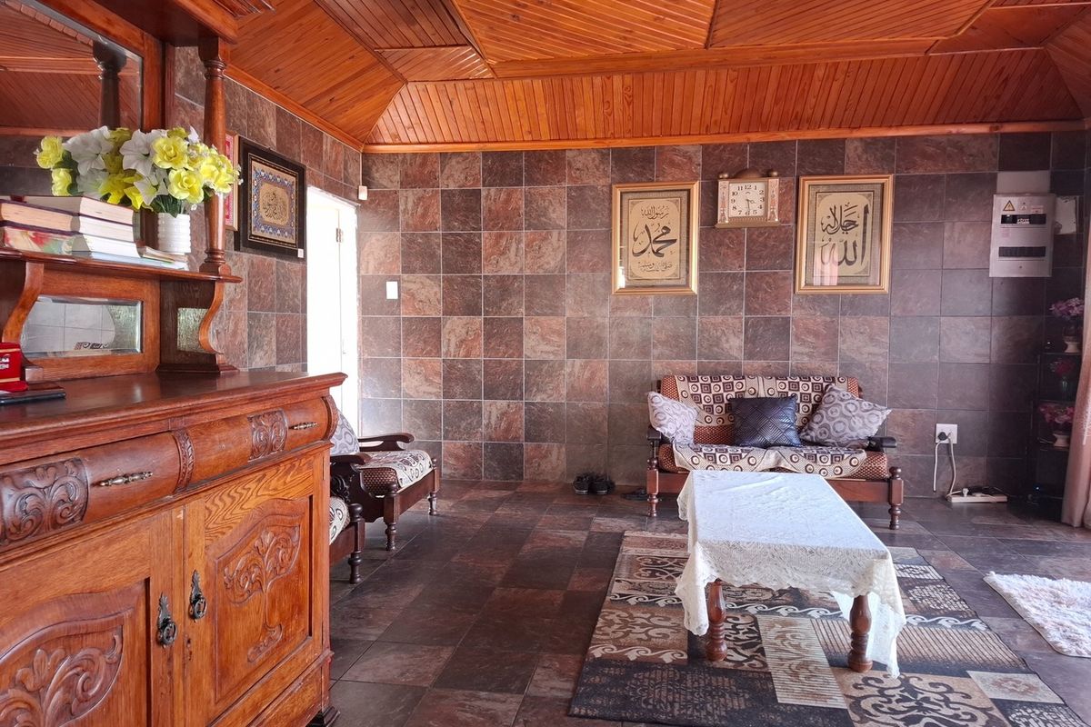 A living room featuring distinctive timber tongue and groove ceiling paneling and full-height tiled wall finishes with matching floor tiles.