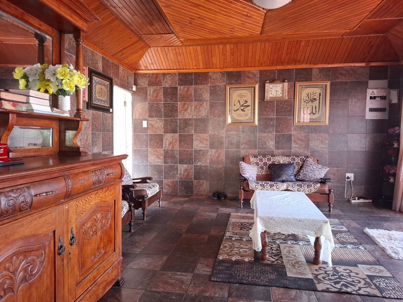 A living room featuring distinctive timber tongue and groove ceiling paneling and full-height tiled wall finishes with matching floor tiles.