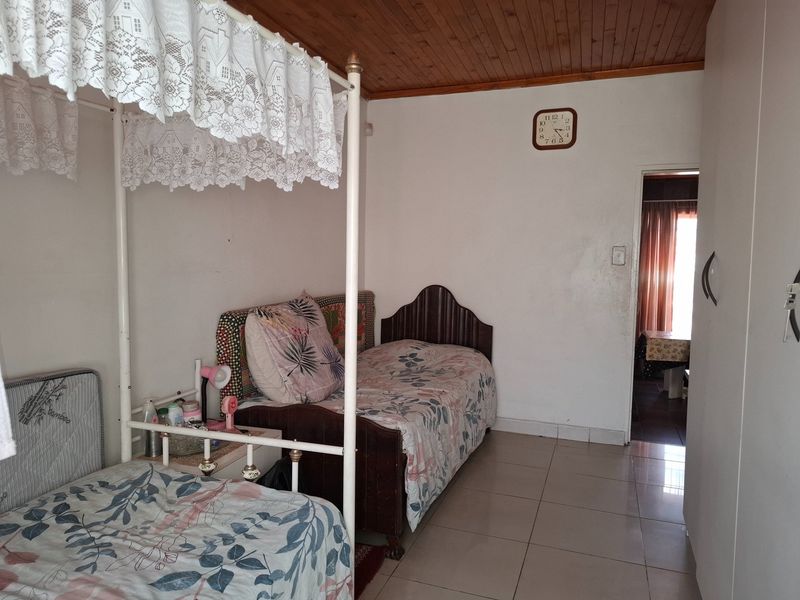 A bedroom featuring ceramic floor tiles and a timber tongue and groove ceiling, with an adjacent doorway leading to another room.