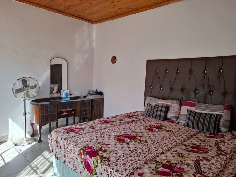 A bedroom featuring tiled flooring and a timber-paneled ceiling, providing a functional space with natural light.