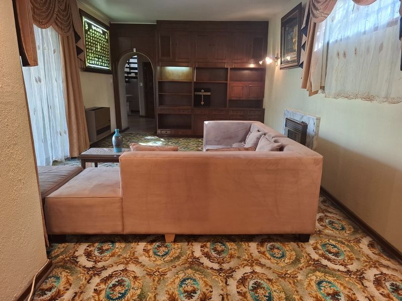 A living room featuring built-in wooden cabinetry, a fireplace, and an arched doorway, finished with traditional patterned carpeting.