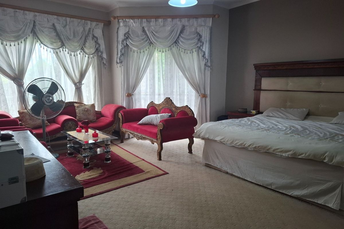 Spacious bedroom featuring large bay windows, neutral carpeting, and a built-in headboard area, offering a comfortable and well-lit living space.
