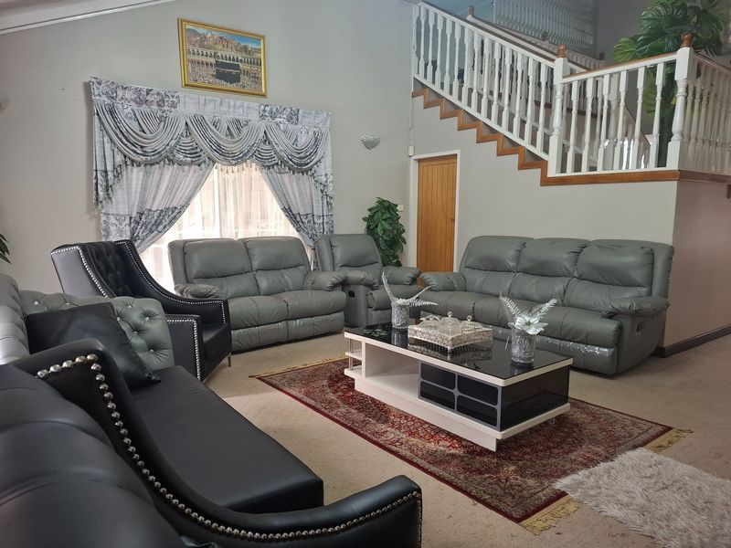 Spacious living room featuring a vaulted ceiling and a prominent staircase with a wooden balustrade.