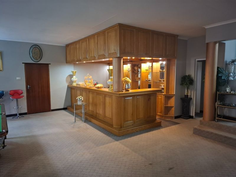 A dedicated home bar area featuring custom built-in wooden cabinetry, a solid bar counter, and integrated lighting, providing a classic entertainment space.