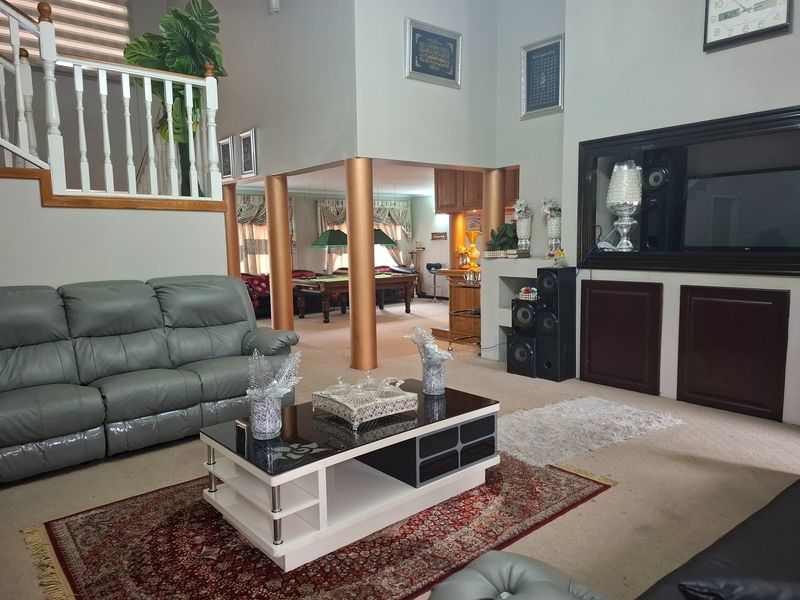 Spacious open-plan living area featuring a staircase with a wooden balustrade, decorative columns, and a built-in media cabinet with recessed shelving.
