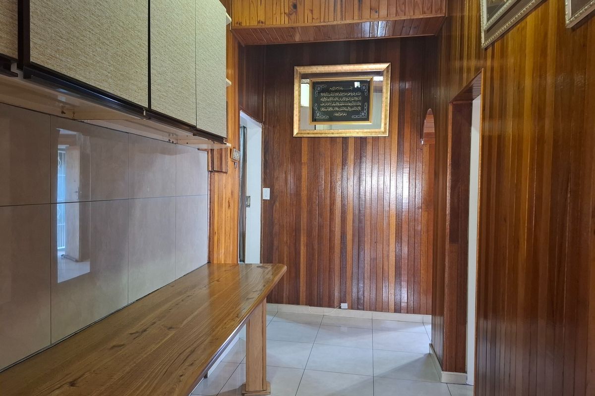 A kitchen area featuring extensive wooden wall and ceiling paneling, tiled flooring, and built-in wooden cabinetry and counter space.