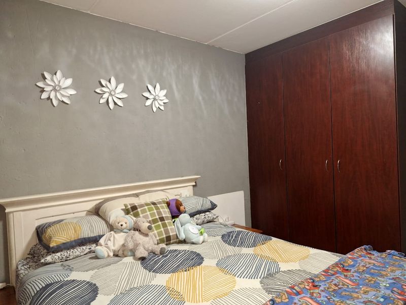 A bedroom featuring a dark wood built-in wardrobe and a grey accent wall.