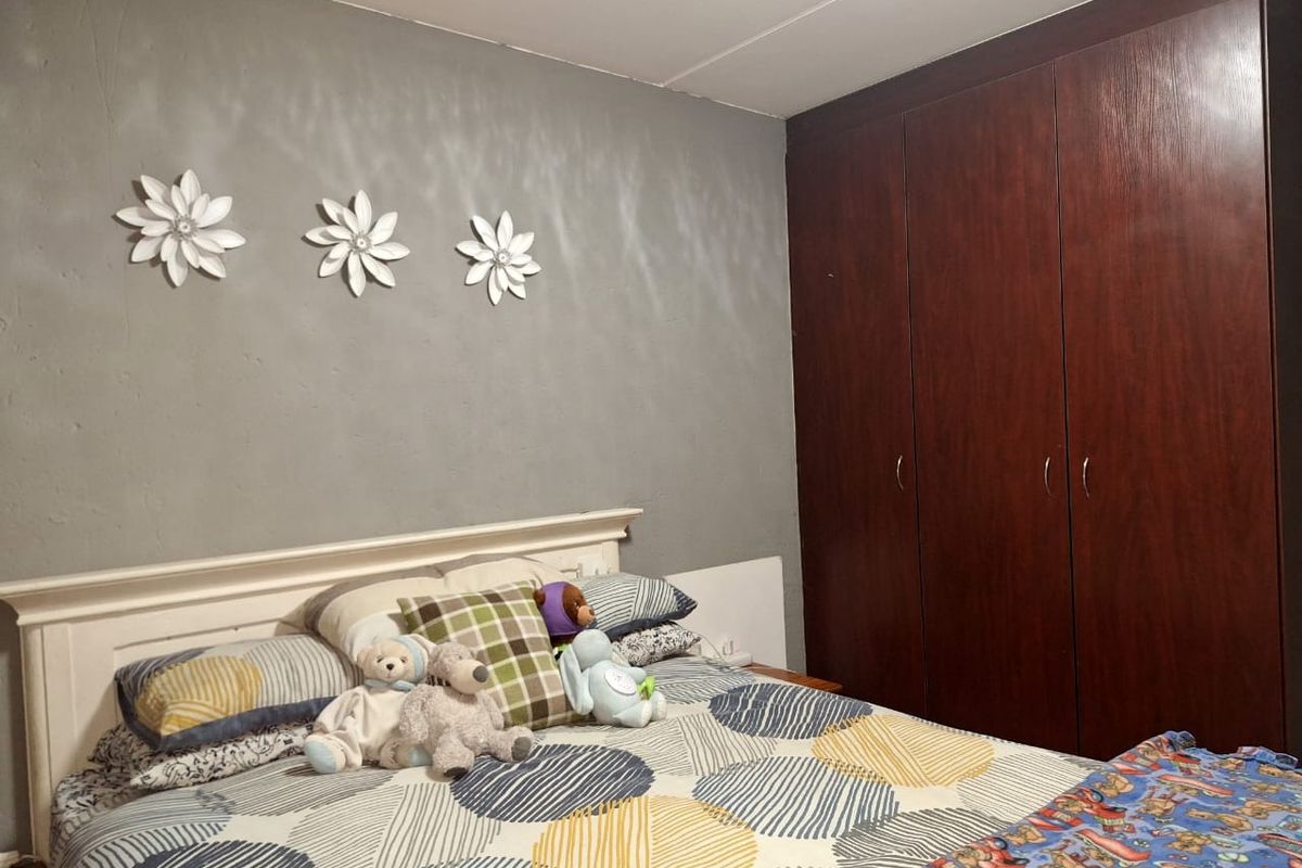 A bedroom featuring a dark wood built-in wardrobe and a grey accent wall.