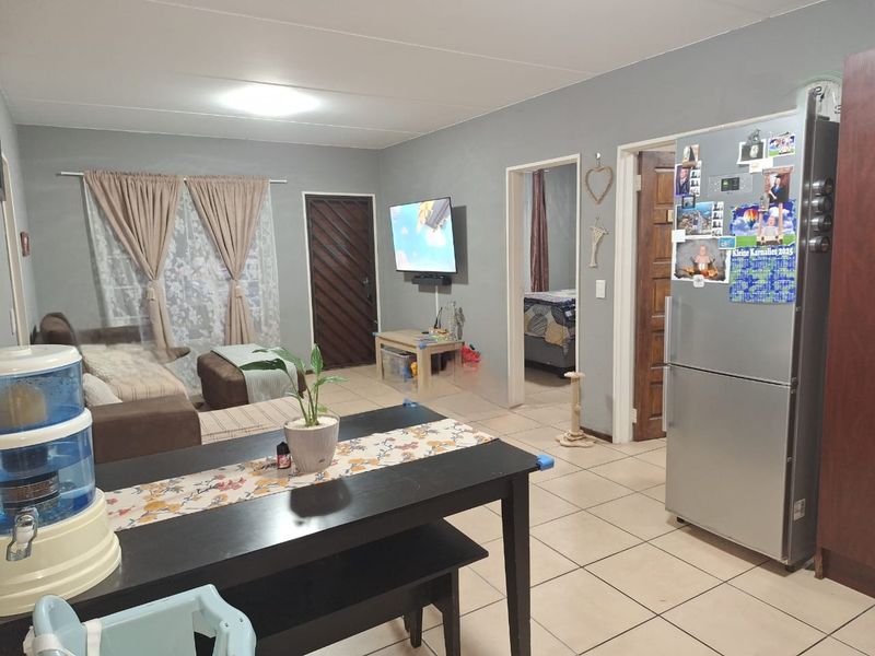 Open plan living area featuring tiled flooring and neutral wall finishes, providing a functional space with direct access to adjacent rooms.