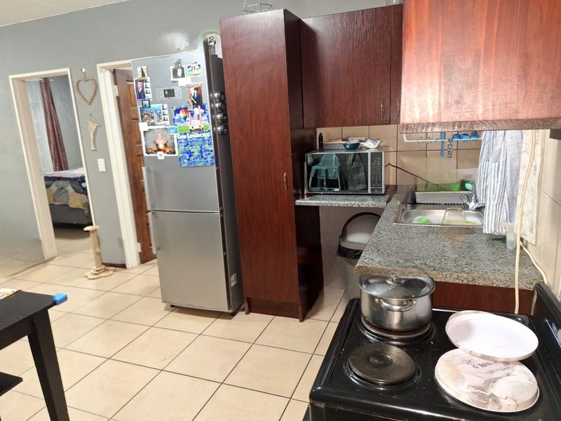 A functional kitchen featuring dark wood cabinetry, granite countertops, tiled flooring, and a built-in electric stove, offering a practical layout for daily meal preparation.