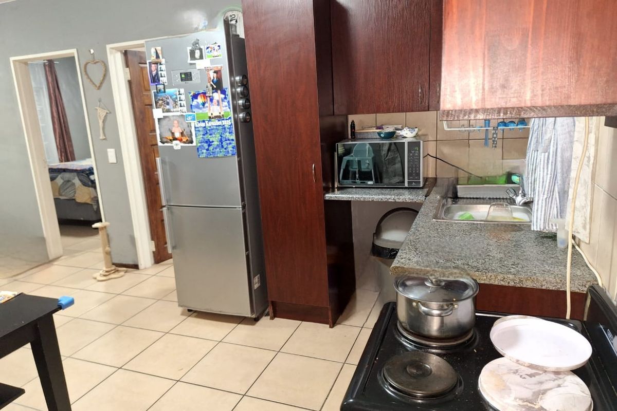 A functional kitchen featuring dark wood cabinetry, granite countertops, tiled flooring, and a built-in electric stove, offering a practical layout for daily meal preparation.