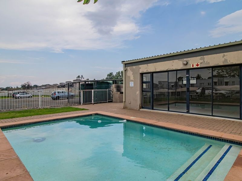 Outdoor pool area featuring a paved deck, perimeter fencing, and access to the building via sliding glass doors, requiring exterior maintenance.