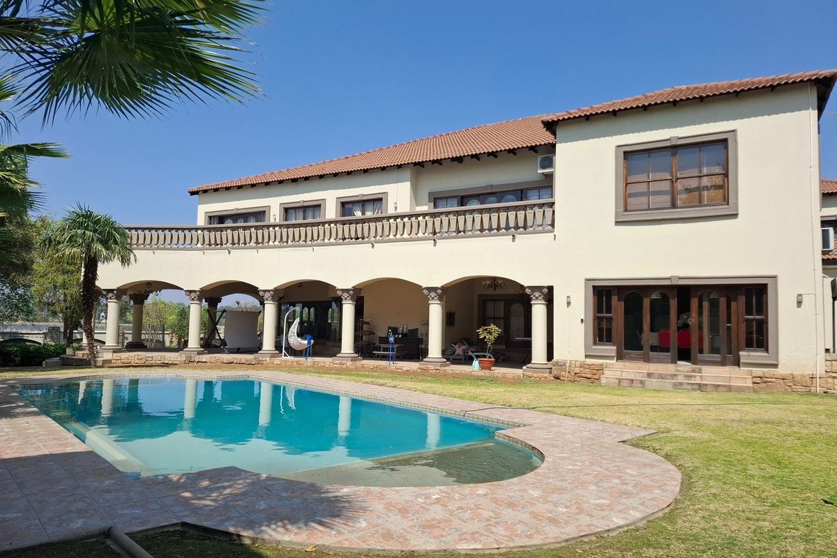 Spacious rear exterior featuring a swimming pool, covered patio with arched columns, and a large upper-level balcony with stone balustrades.