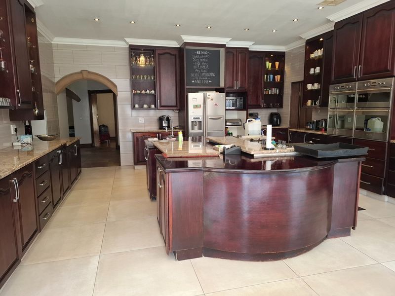 Spacious kitchen featuring dark wood cabinetry, granite countertops, a large central island, and built-in double ovens with recessed lighting.