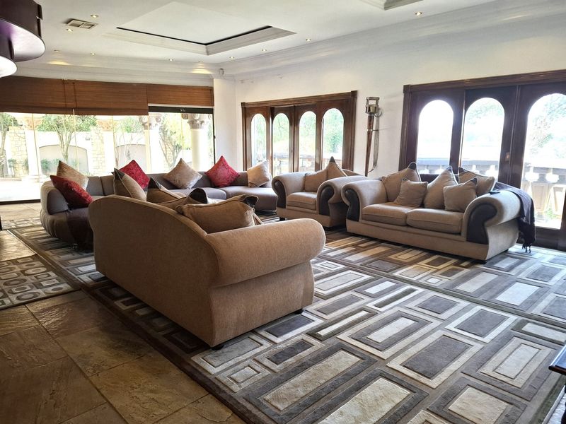 Spacious living room featuring stone flooring, recessed ceiling lighting, and large arched timber-framed doors providing access to the outdoor area.