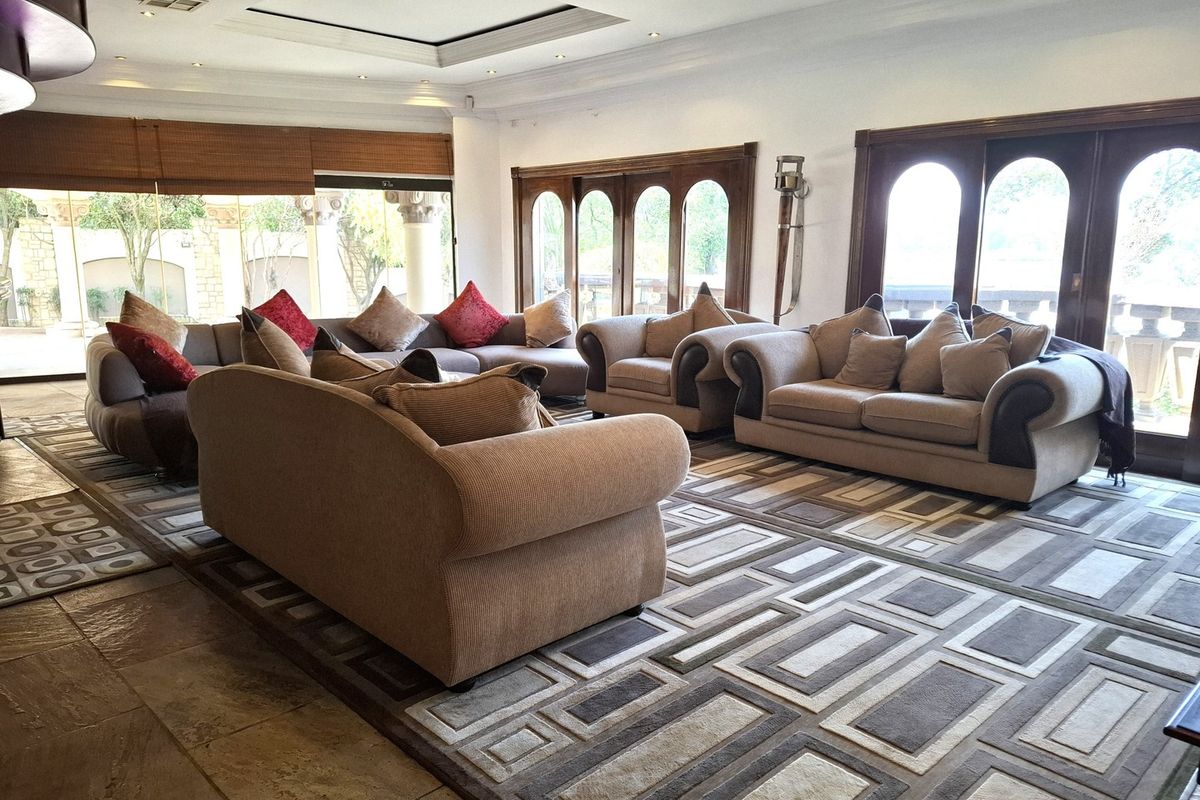 Spacious living room featuring stone flooring, recessed ceiling lighting, and large arched timber-framed doors providing access to the outdoor area.