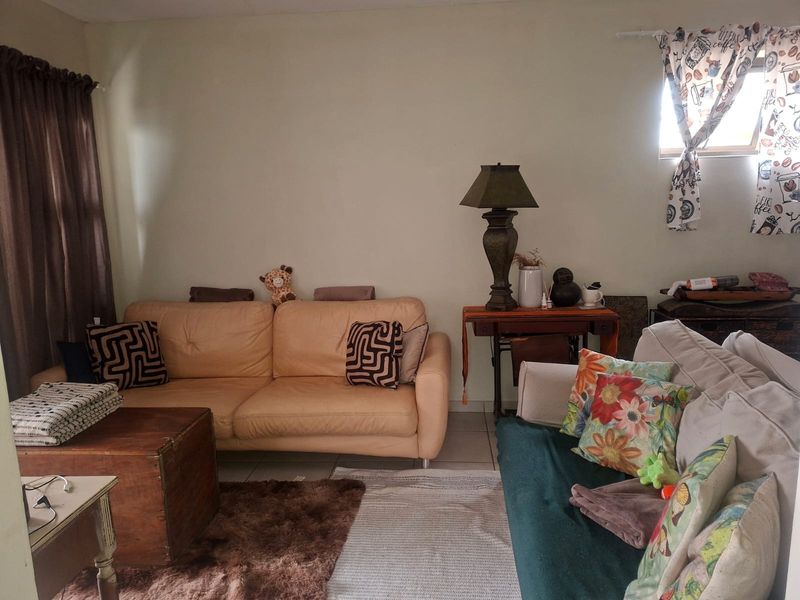 A living room area featuring tiled flooring and natural light from a side window.