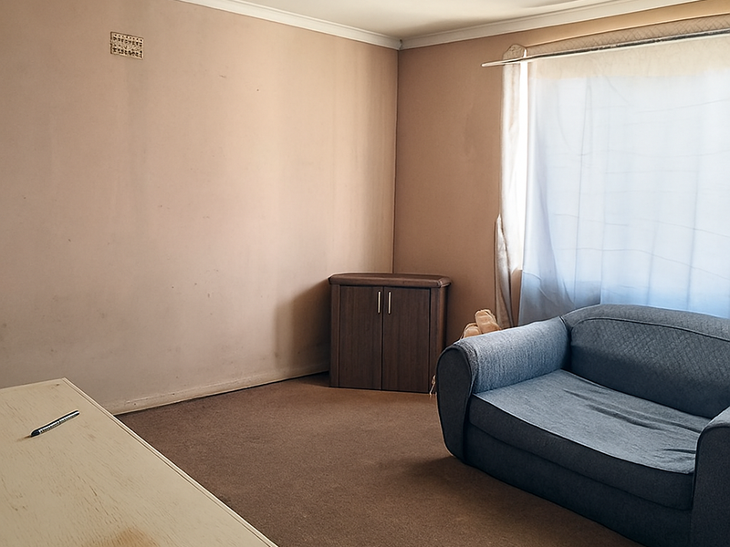 A living room space featuring neutral wall tones, carpet flooring, and coving, offering a blank canvas for potential interior updates.