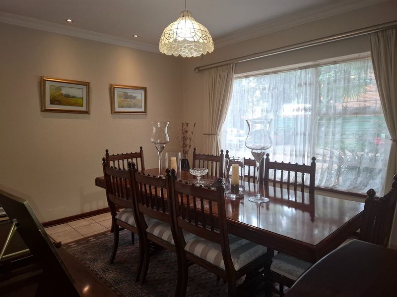 A formal dining room featuring tiled flooring, coved cornicing, and a large window providing natural light, suitable for family meals and entertaining.